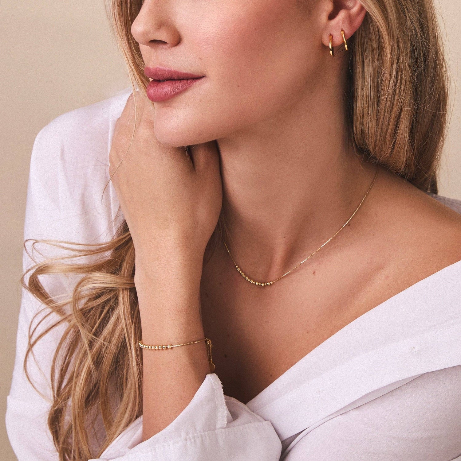 Women in white blouse wearing FYB Addison gold bracelet and necklace