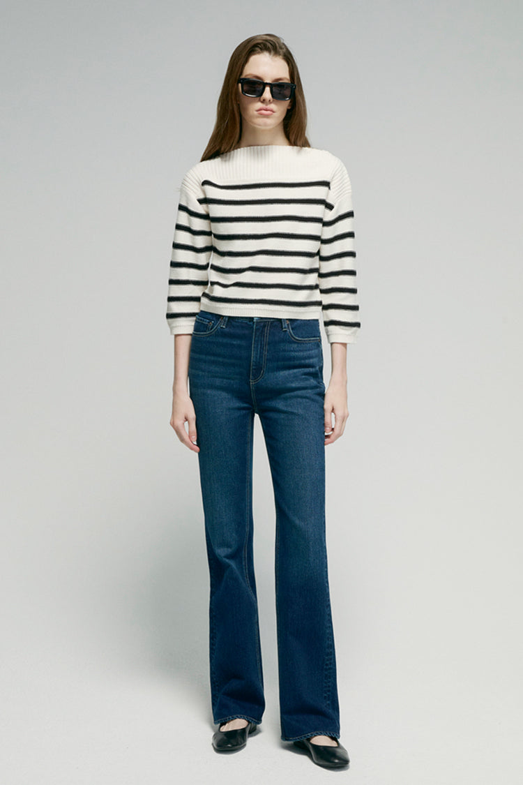 Person wearing a striped sweater and blue jeans on a plain background