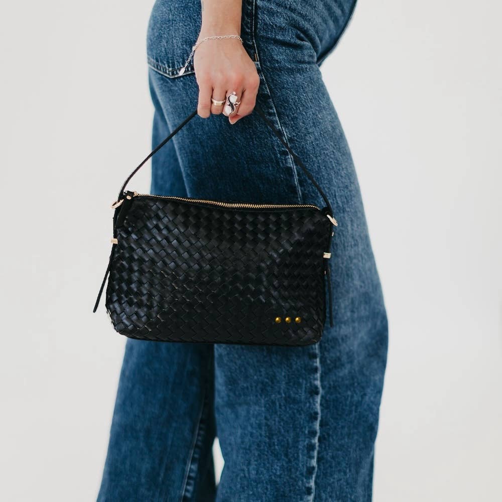 Person holding a black textured handbag with a plain background