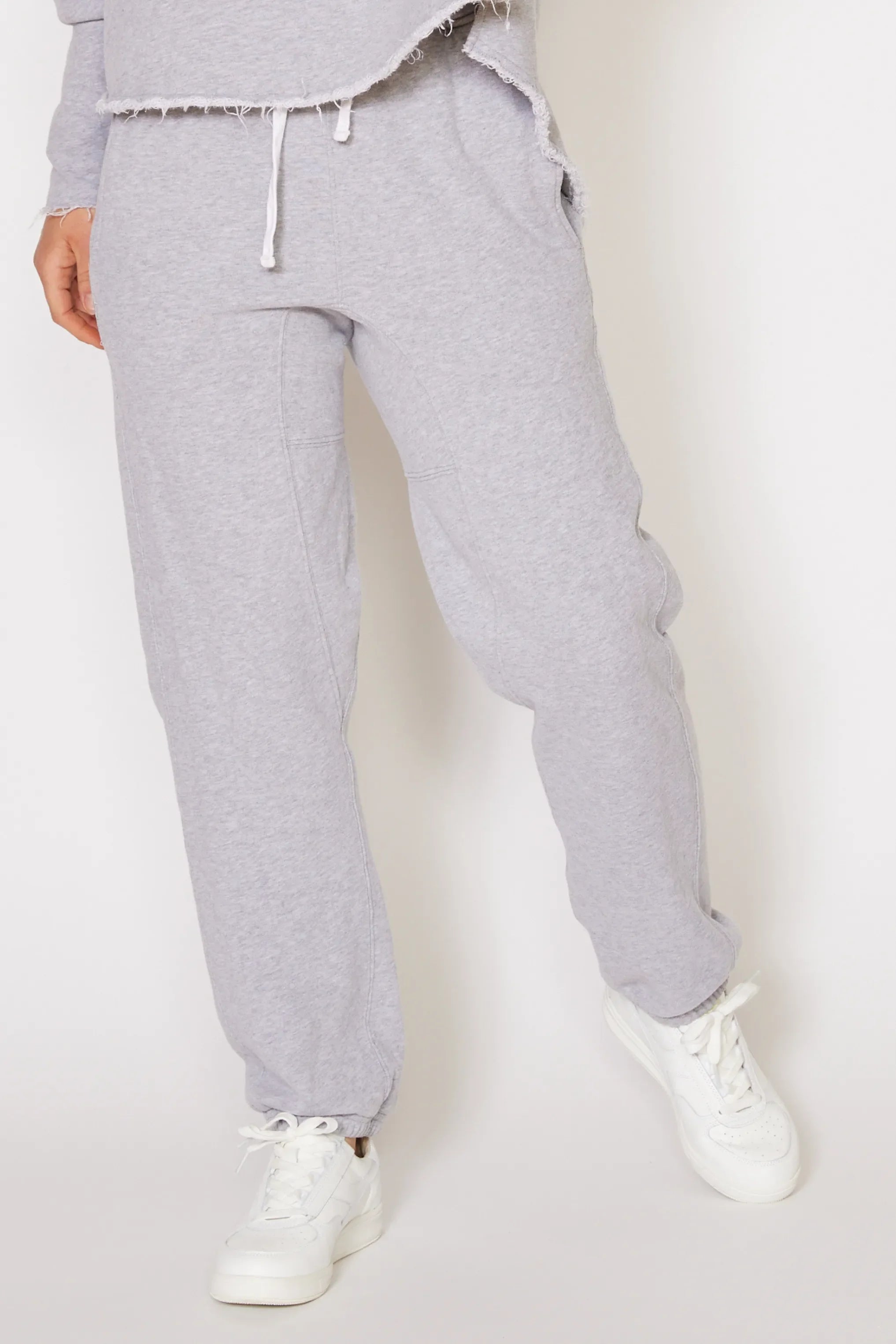 Person wearing gray sweatpants and white sneakers on a white background