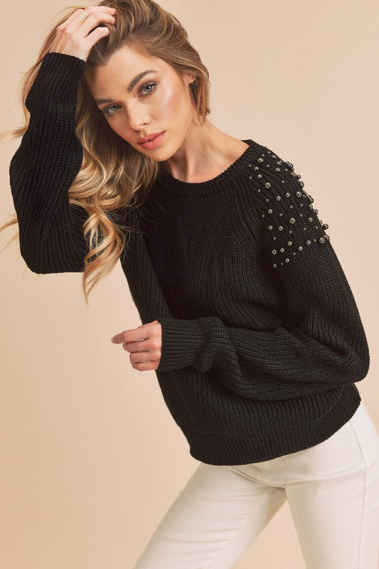 Sylvia Embellished Shoulder Sweater in black worn by a model, with white jeans
