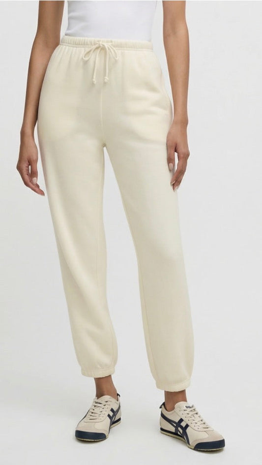 Person wearing cream jogger pants and white sneakers on a light gray background