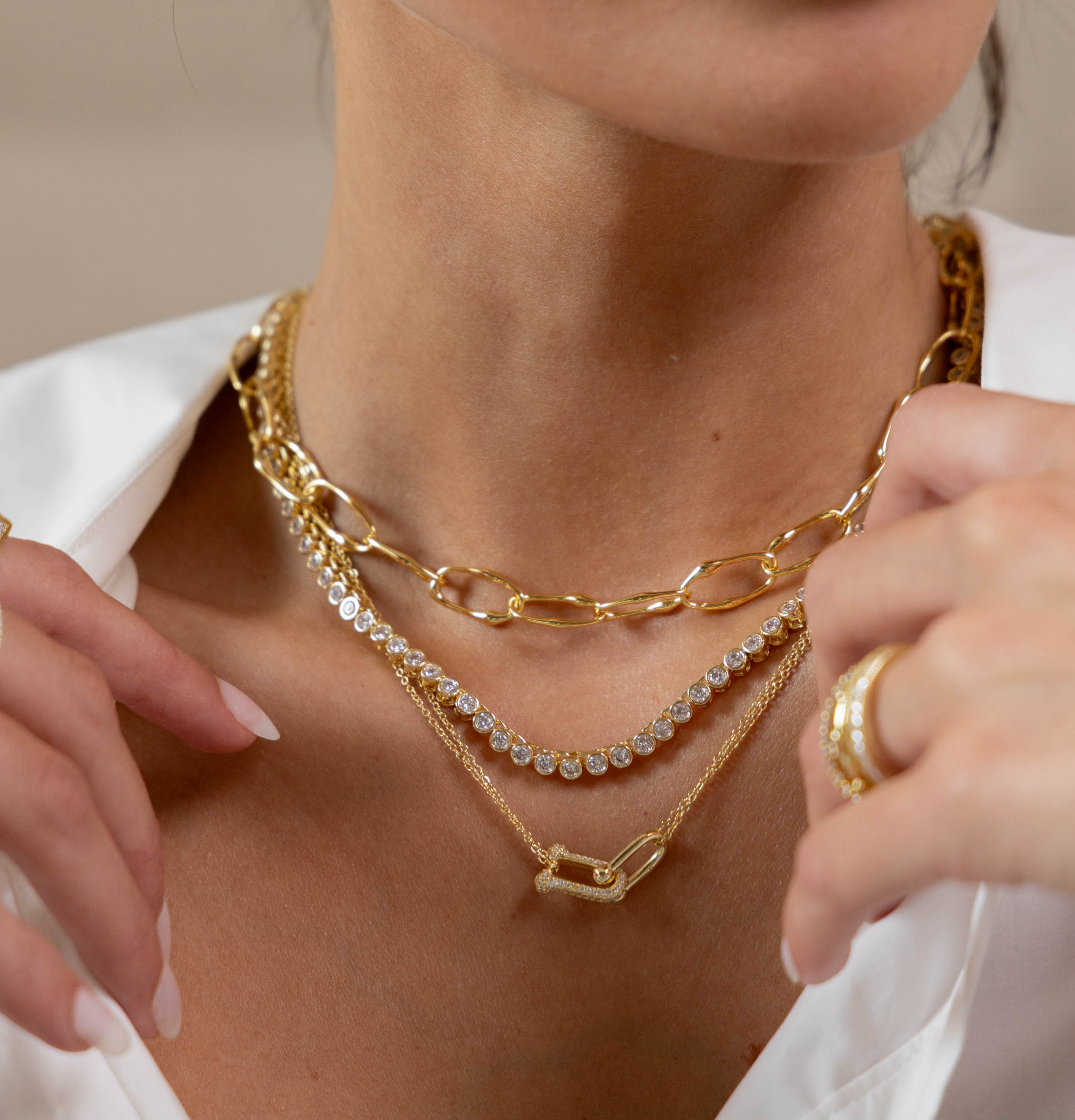Close-up of a person wearing multiple gold necklaces and a ring.