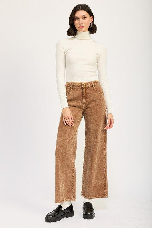 Women wearing a cream mock neck sweater and sepia colored distressed corduroy pants and black loafers