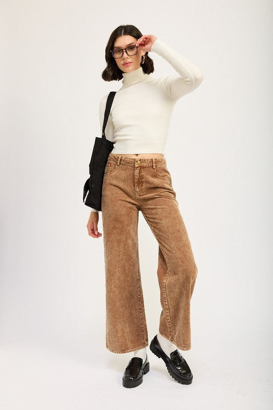 Women with glasses wearing a cream mock neck sweater and sepia colored distressed corduroy pants