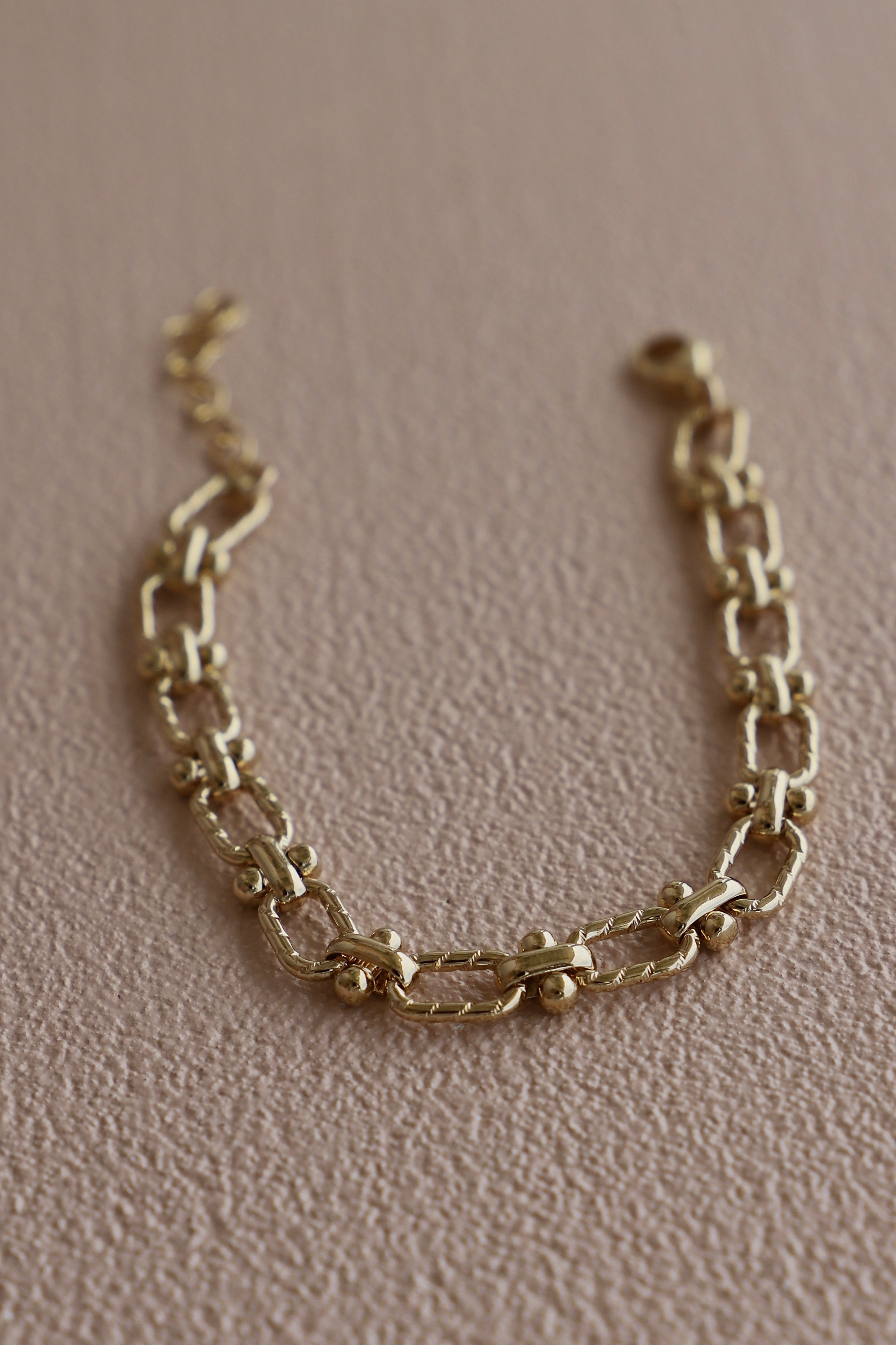 Gold chain bracelet on a beige background