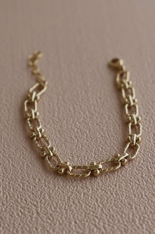 Gold chain bracelet on a beige background