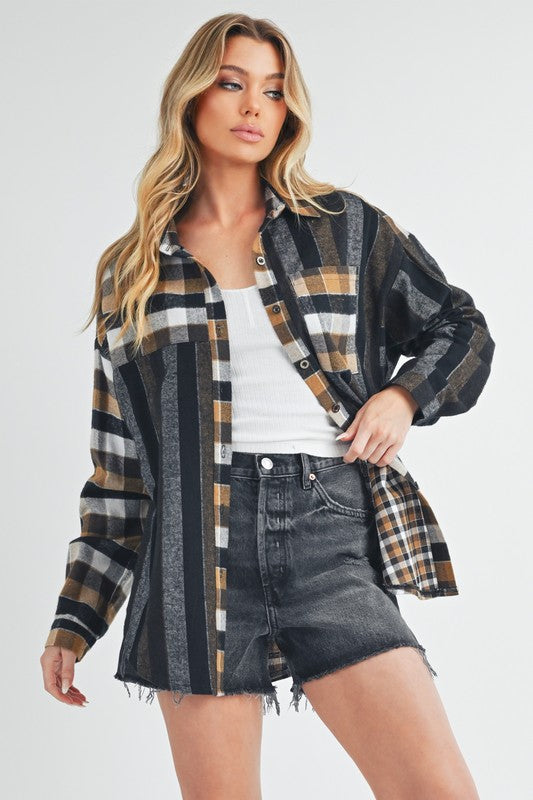 A woman with blonde hair wearing the Lena multi-plaid flannel shirt, styled open over a white t-shirt and dark wash jeans shorts