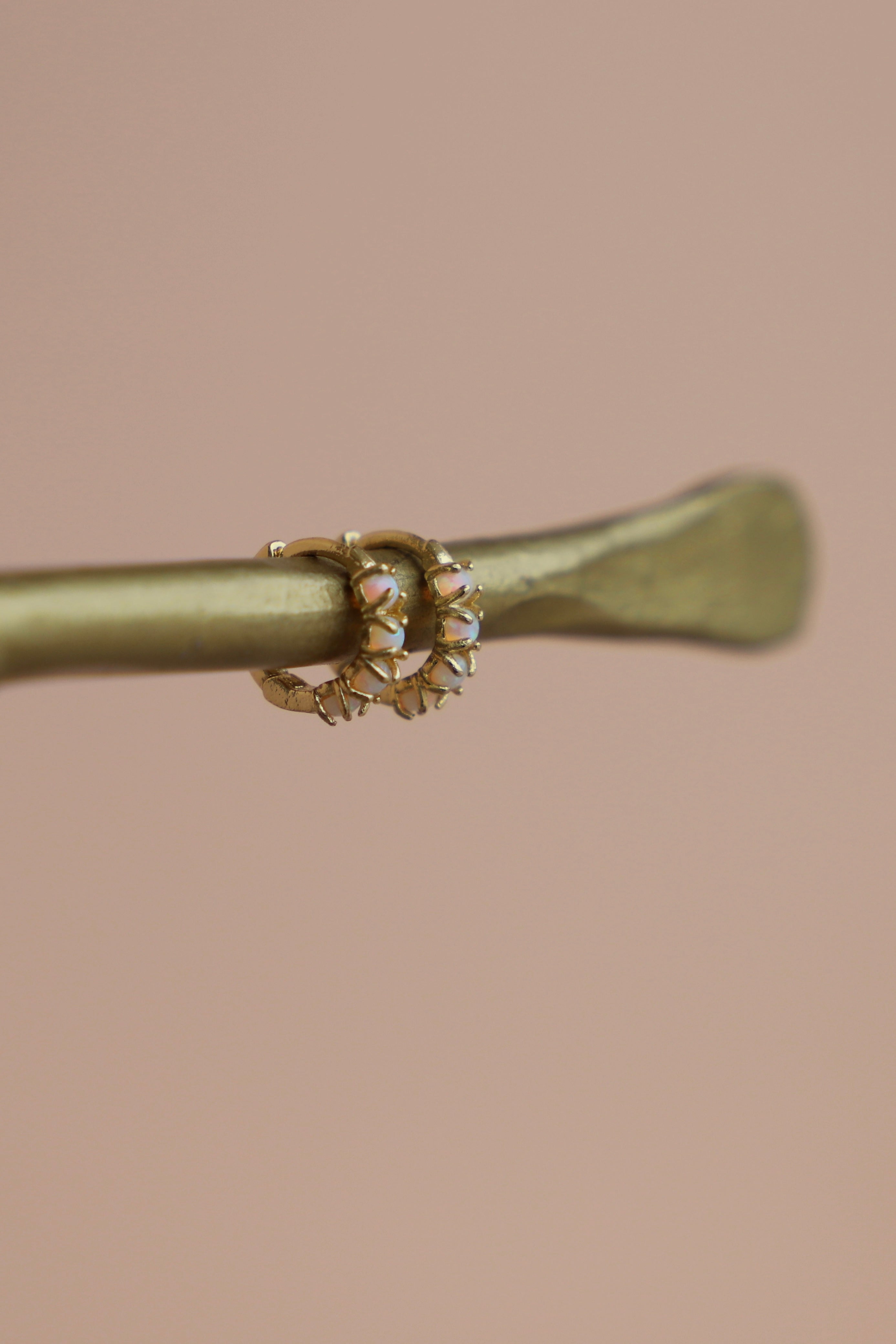 Gold ring with a central gemstone on a beige background