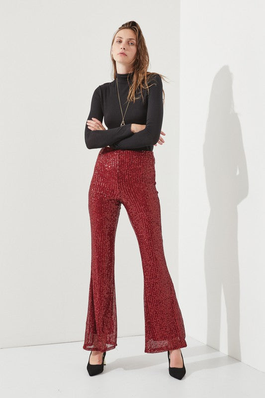 Woman in black turtleneck and burgundy sequin leggings