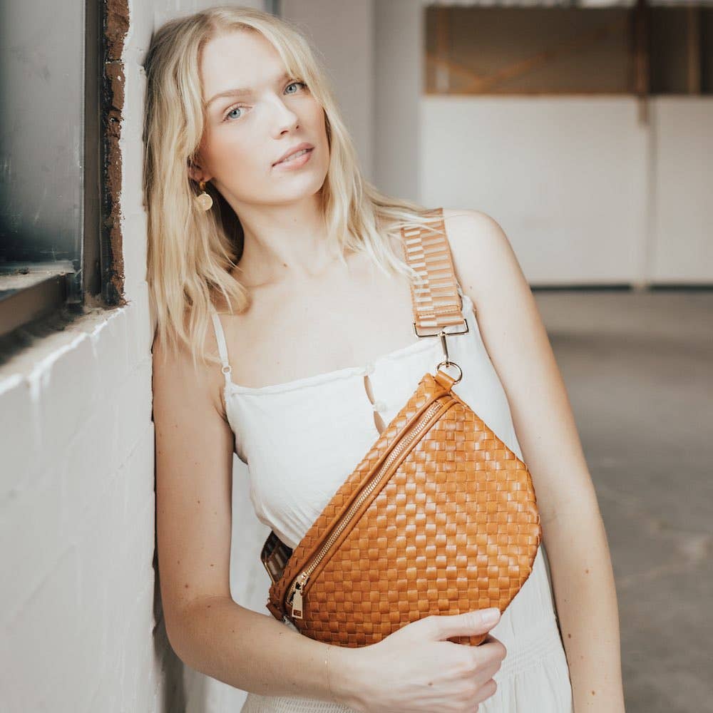 Woman holding a woven brown bag in an indoor setting