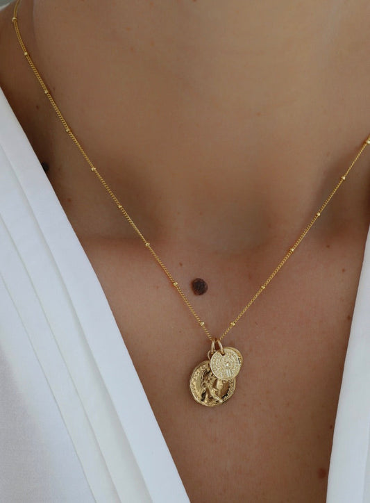 Gold filled satellite cable chain necklace with two interchangeable gold plate brass coin charms, shown in multiple styling options for versatile wear.