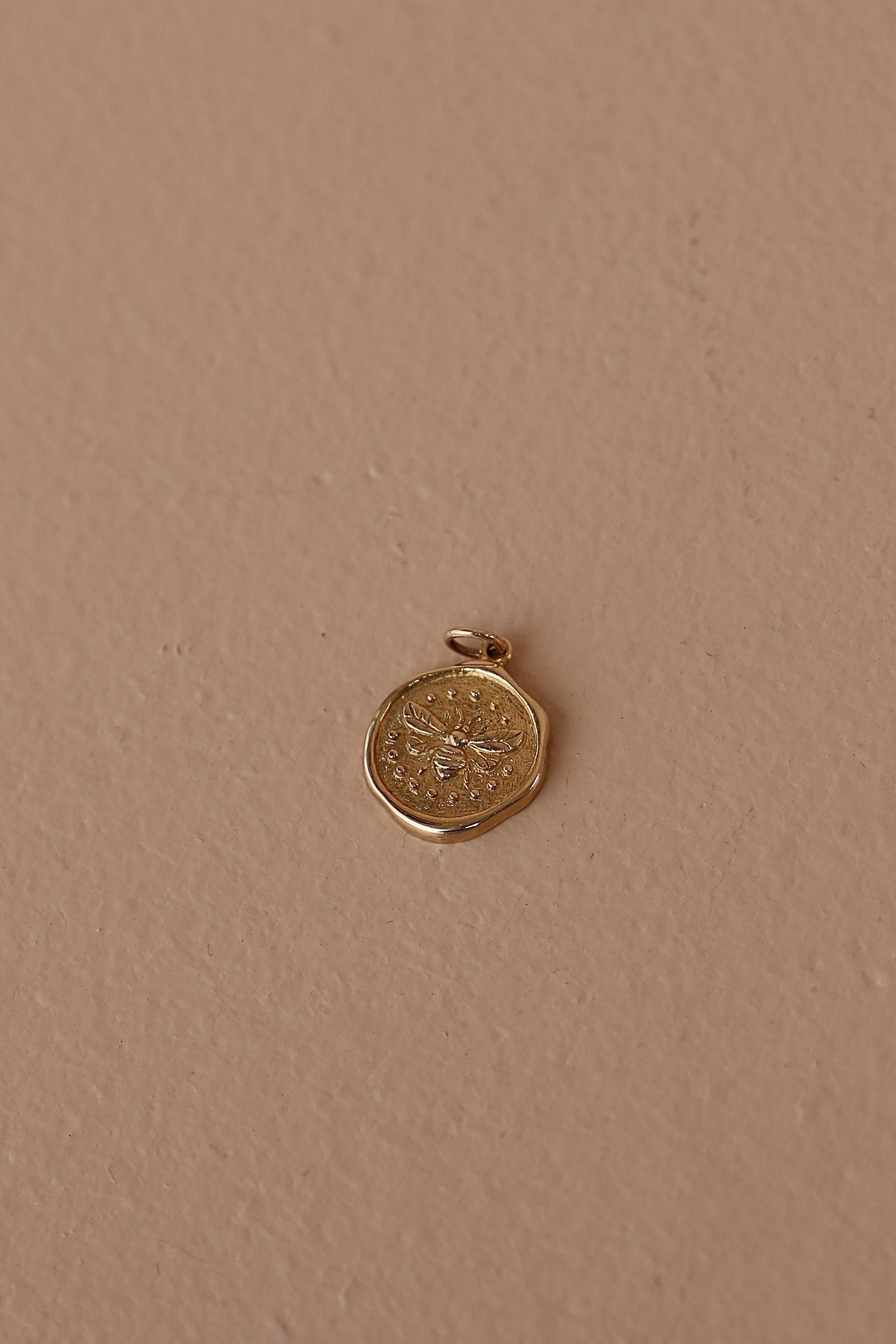 Wax seal bee charm on a beige background