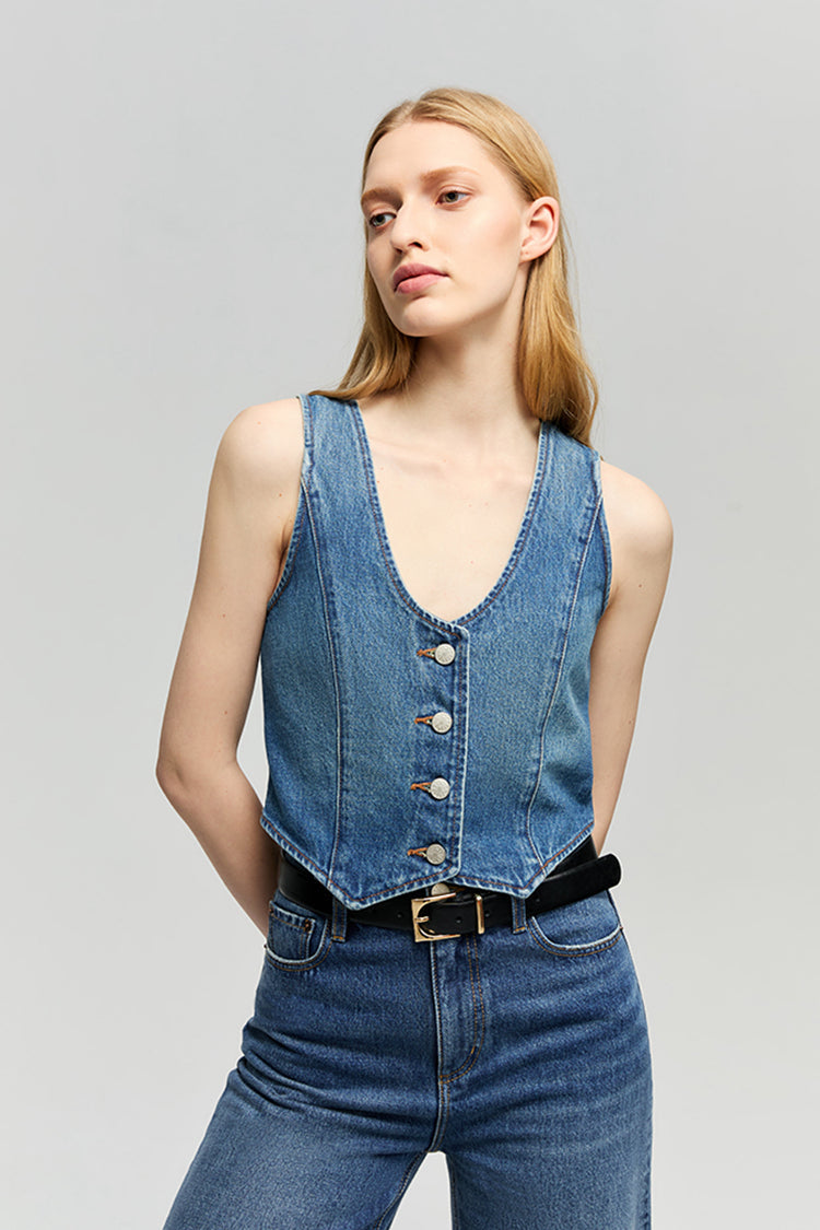 Woman wearing a denim vest and jeans on a gray background