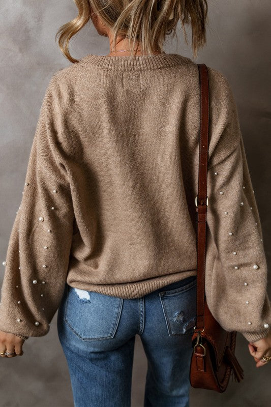 Back side of model wearing light brown pearl accent drop shoulder sweater paired with jeans 
