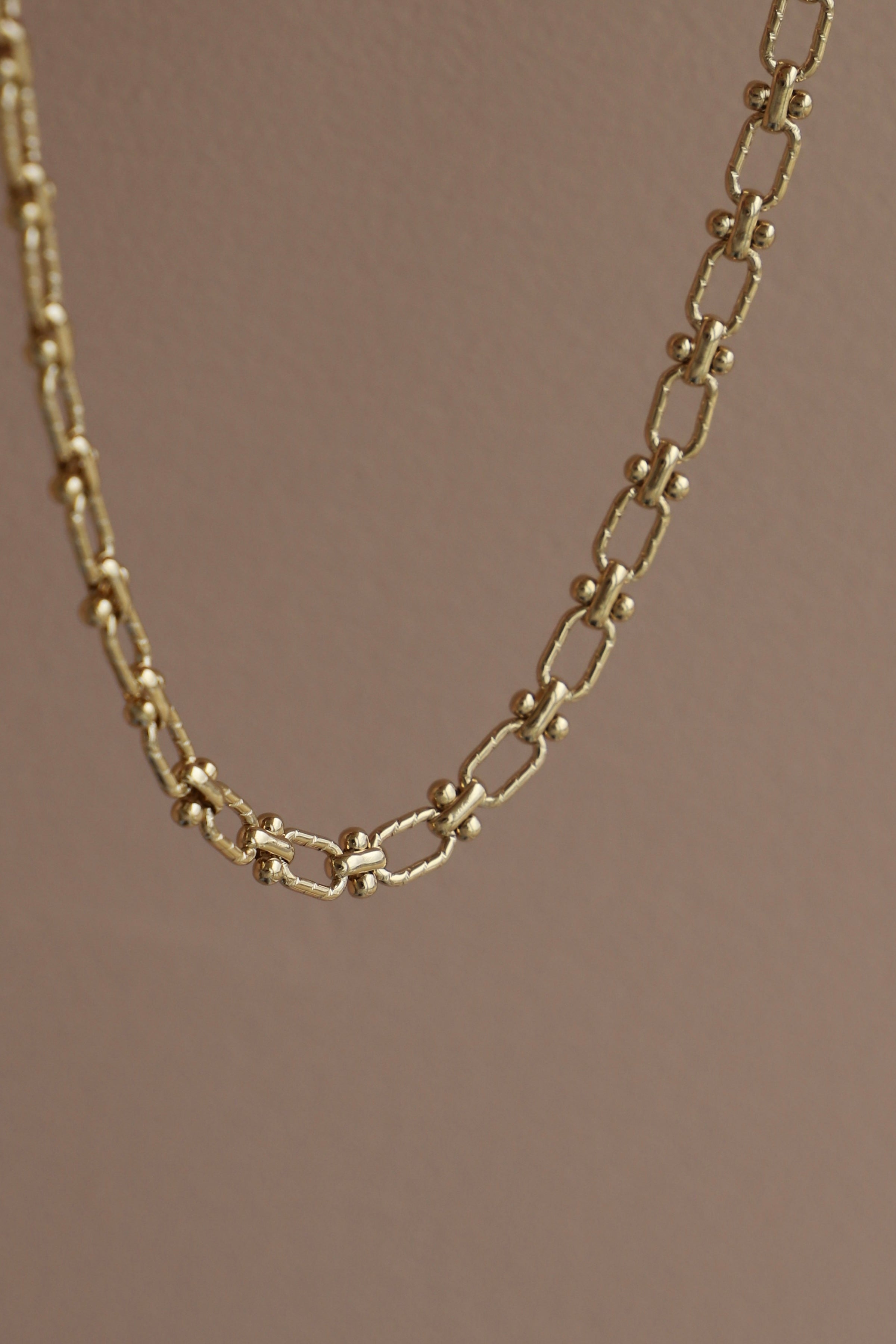Gold chain necklace on a brown background
