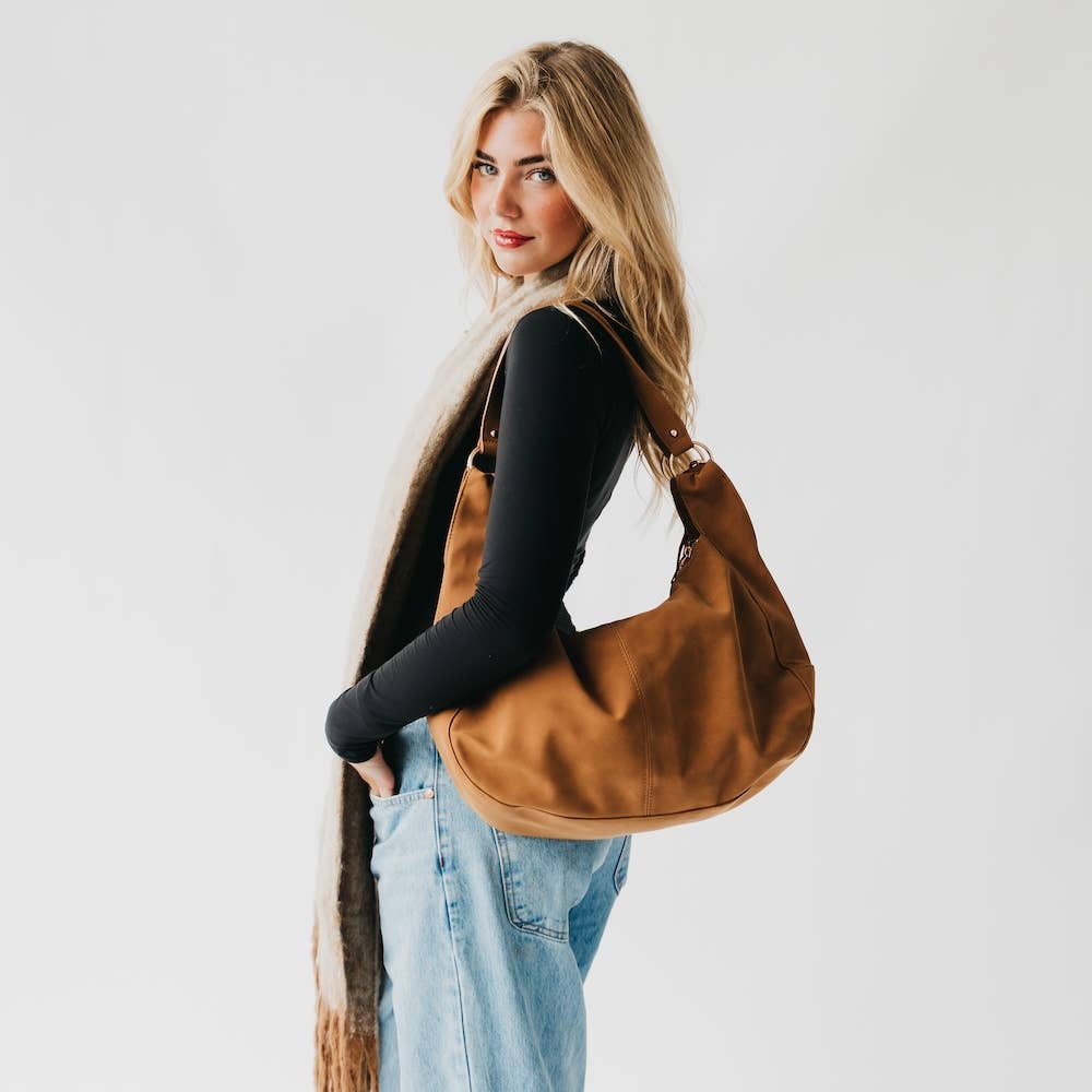 Woman carrying a brown leather bag against a plain background