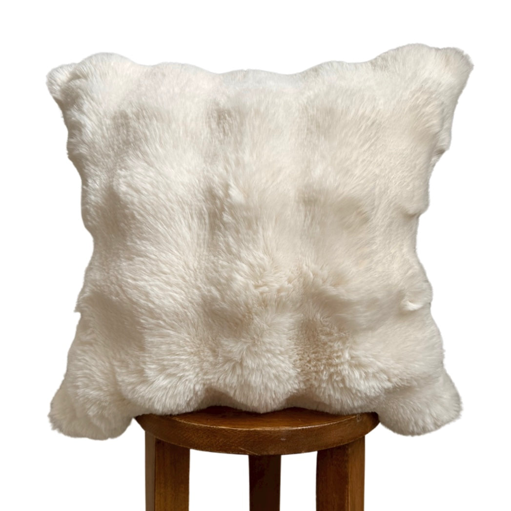 White fluffy pillow on a wooden stool against a white background