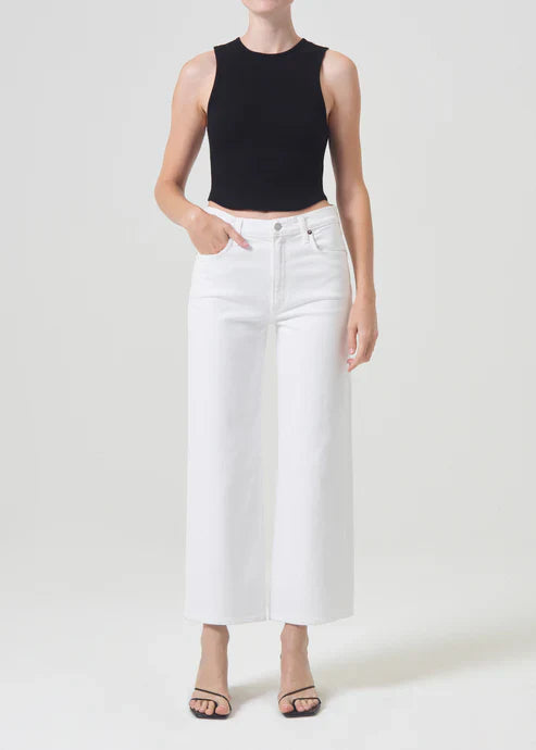 A model wearing Agolde Harper Crop jeans in "Sour Cream," a pair of white, mid-rise jeans with a relaxed, cropped wide-leg fit.