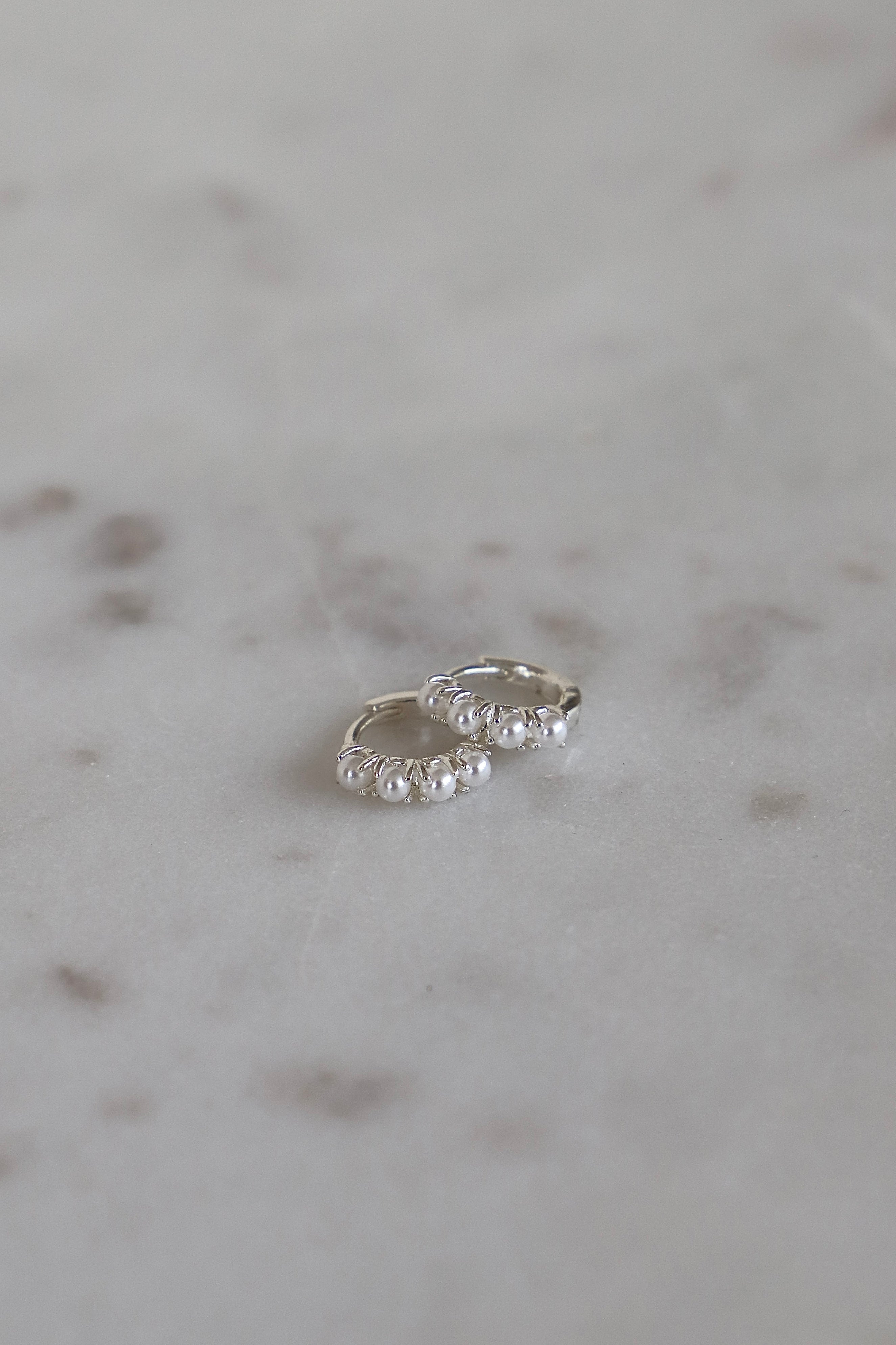 Silver hoop earrings on a marble surface