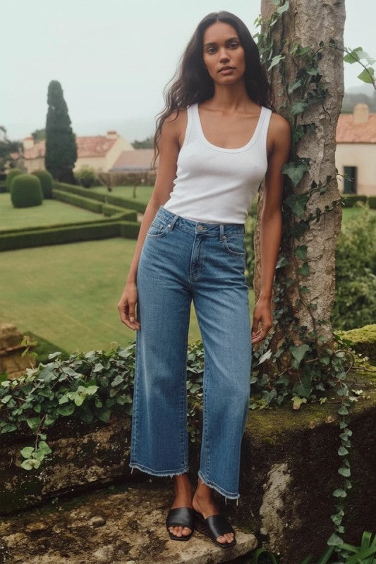Woman wearing medium wash high rise cropped wide leg jeans in stretch denim, Rosie Karma boutique