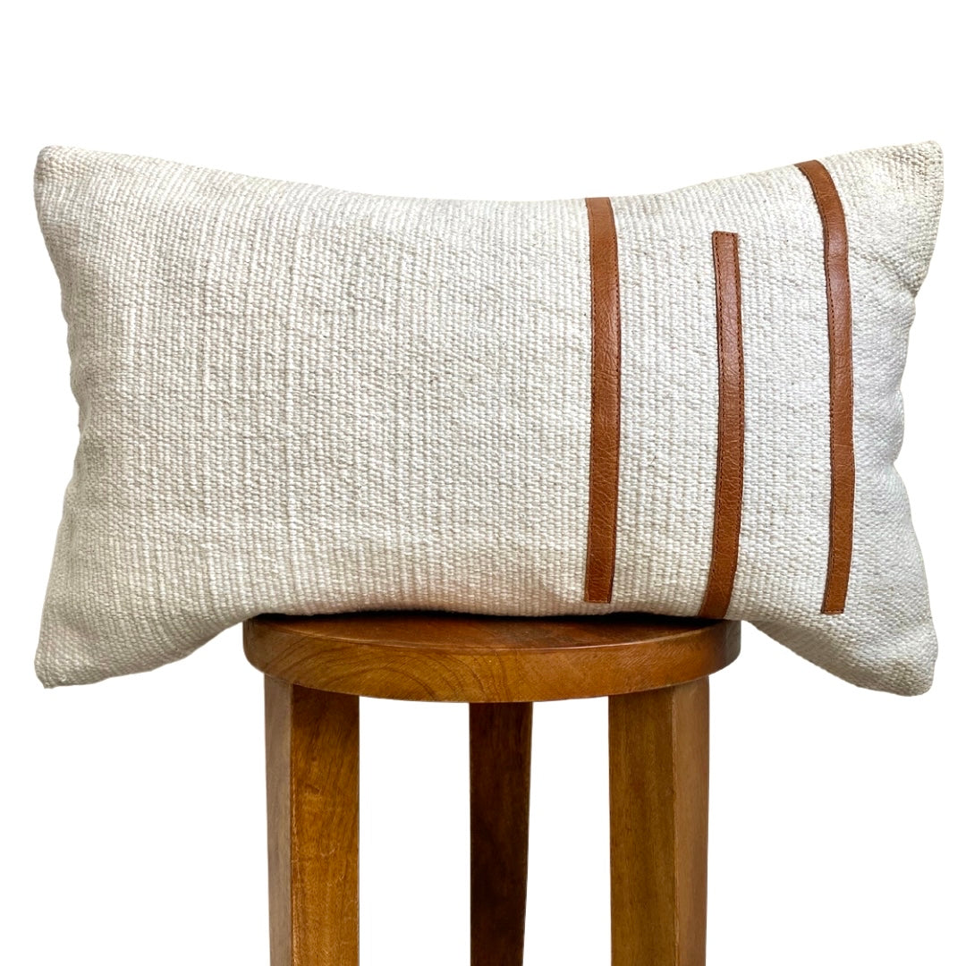 Textured pillow with brown stripes on a wooden stool against a white background