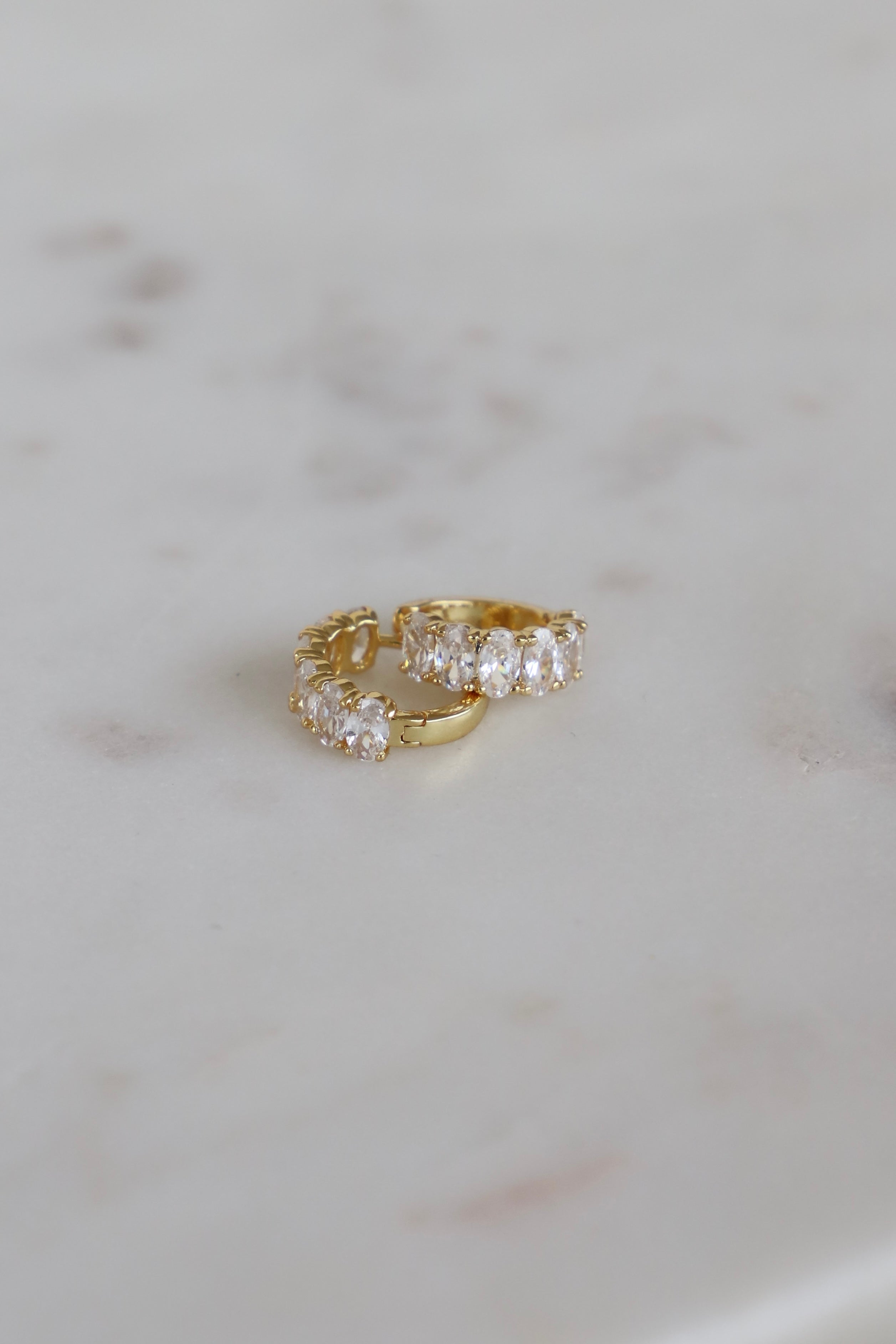 Gold ring with clear gemstones on a marble surface