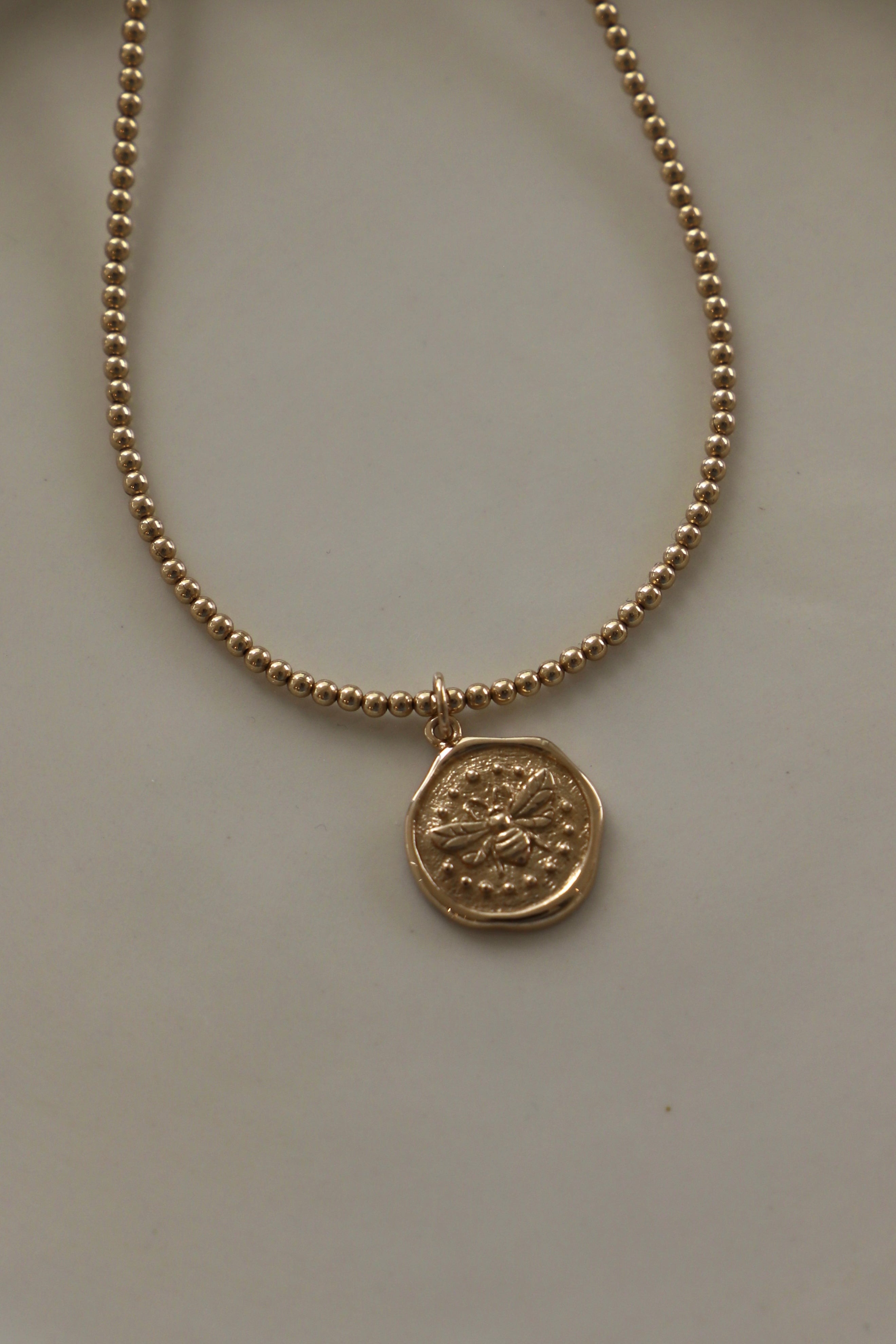 Gold necklace with a wax seal bee charm 