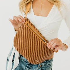 Person holding a brown woven bag with a white background