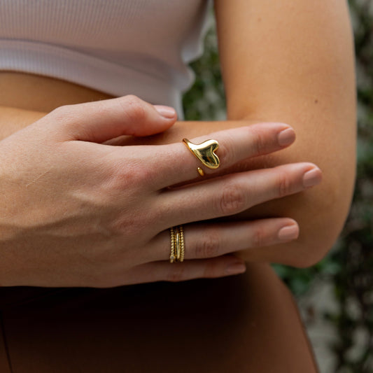 Close-up of a hand wearing gold rings with a blurred natural background