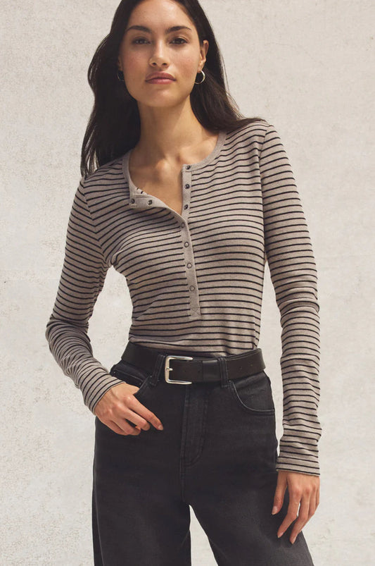 Woman wearing a striped long-sleeve top and black pants against a neutral background