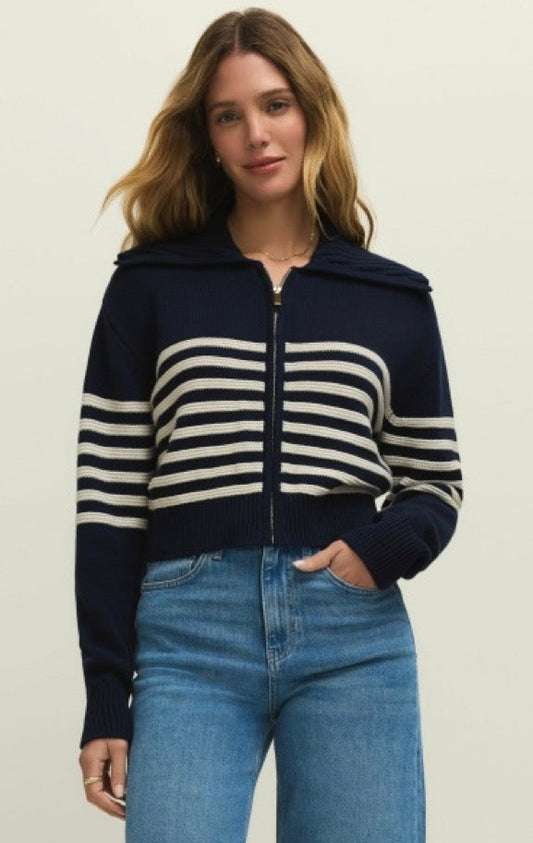Woman wearing a navy and white striped sweater with a hood on a beige background