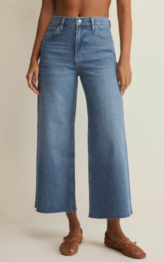 Person wearing blue jeans on a beige background