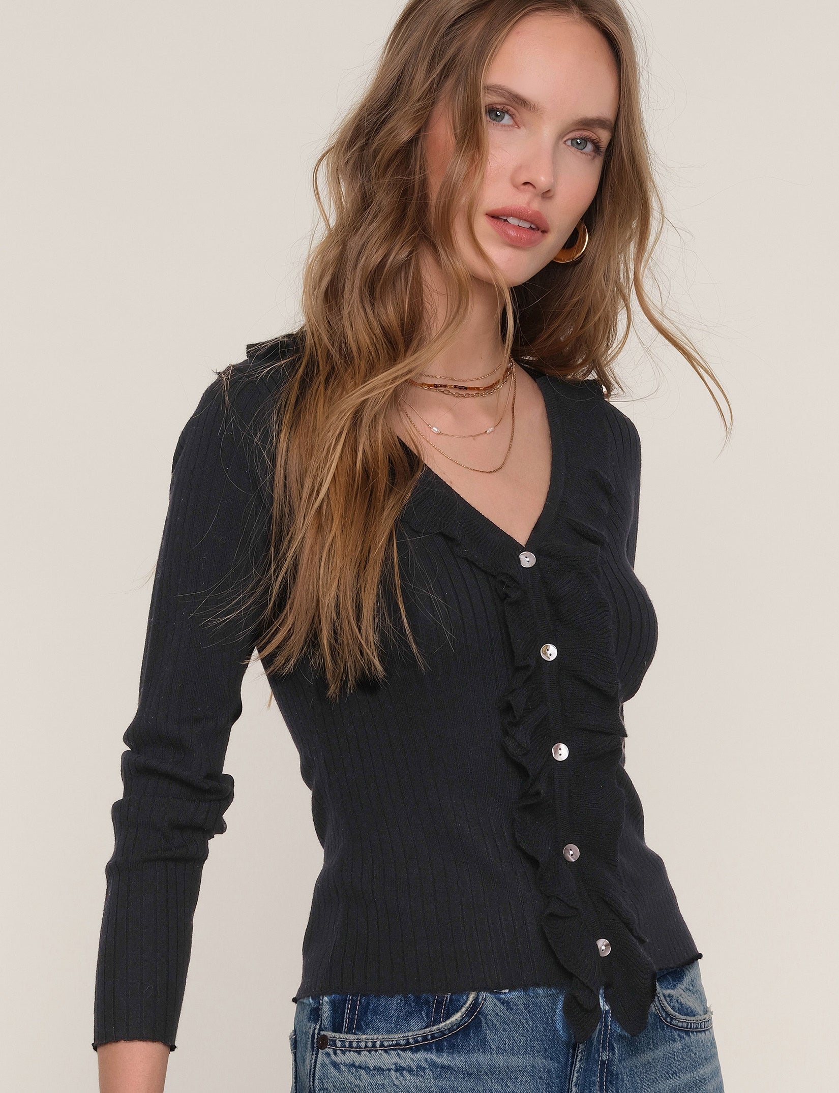 Woman wearing a black cardigan with button details on a plain background
