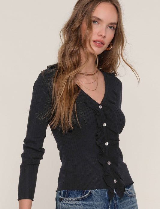Woman wearing a black cardigan with button details on a plain background