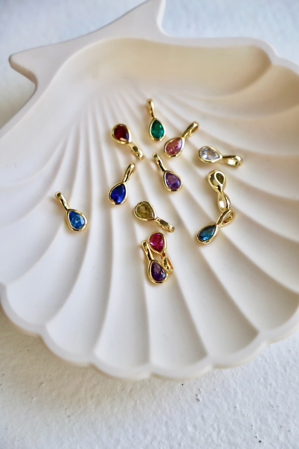 Gold pendants with colorful gemstones on a white shell