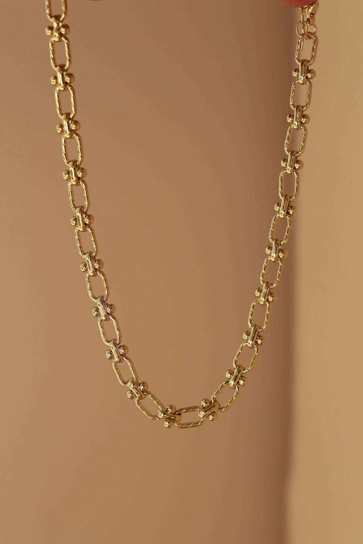 Gold chain necklace on a beige background
