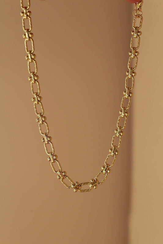 Gold chain necklace on a beige background