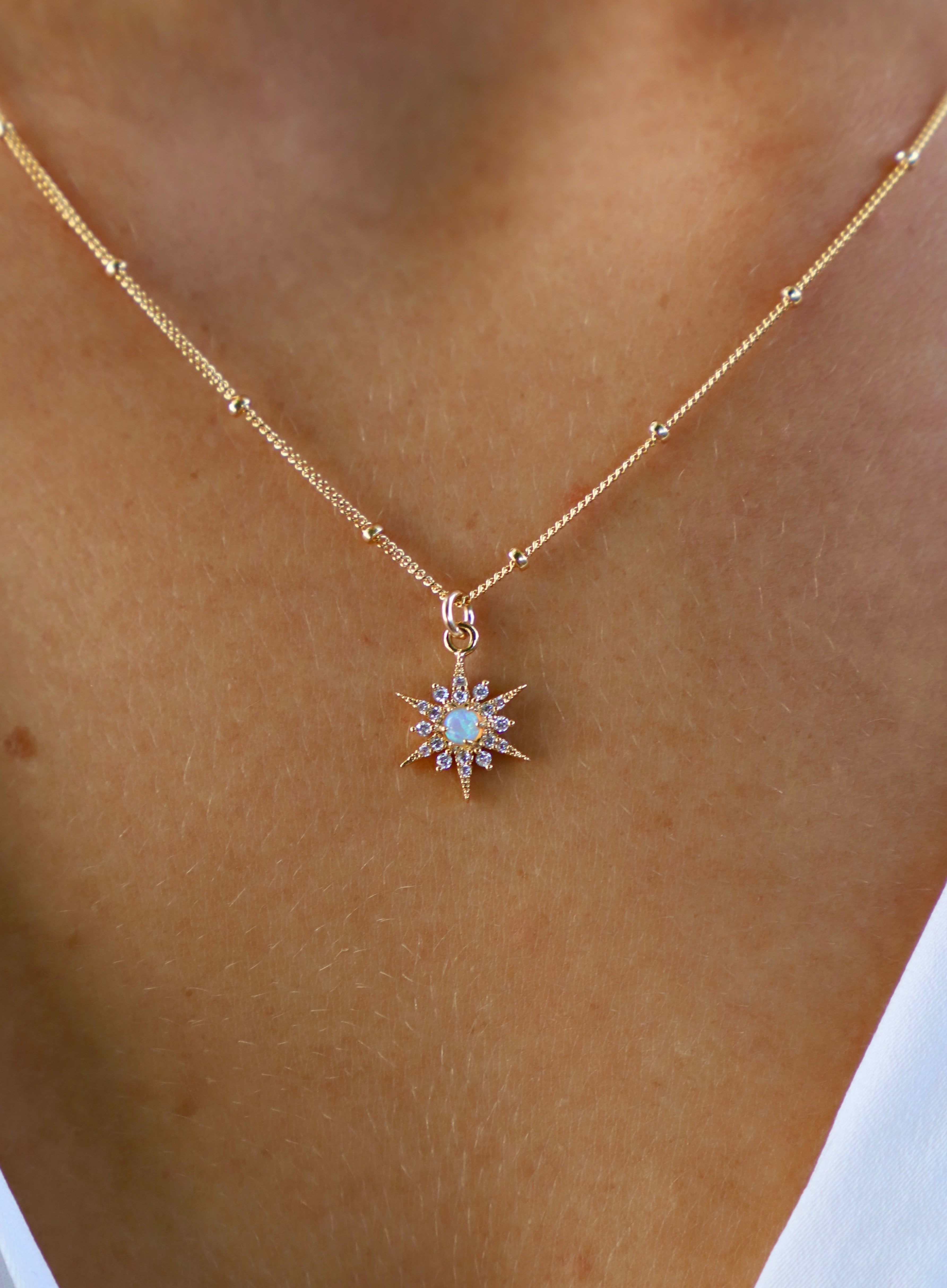 Gold necklace with a star-shaped pendant on a person's neck