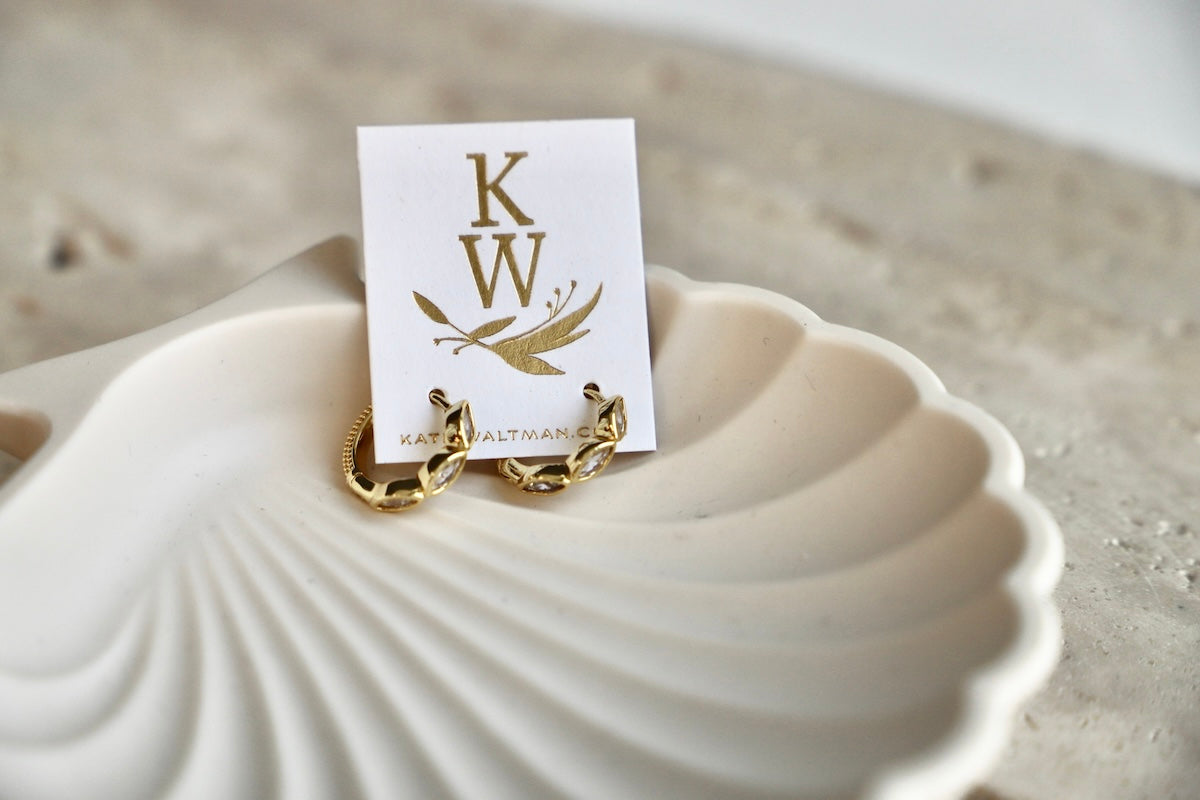 Gold ring on a white shell with a card displaying 'KW' initials.