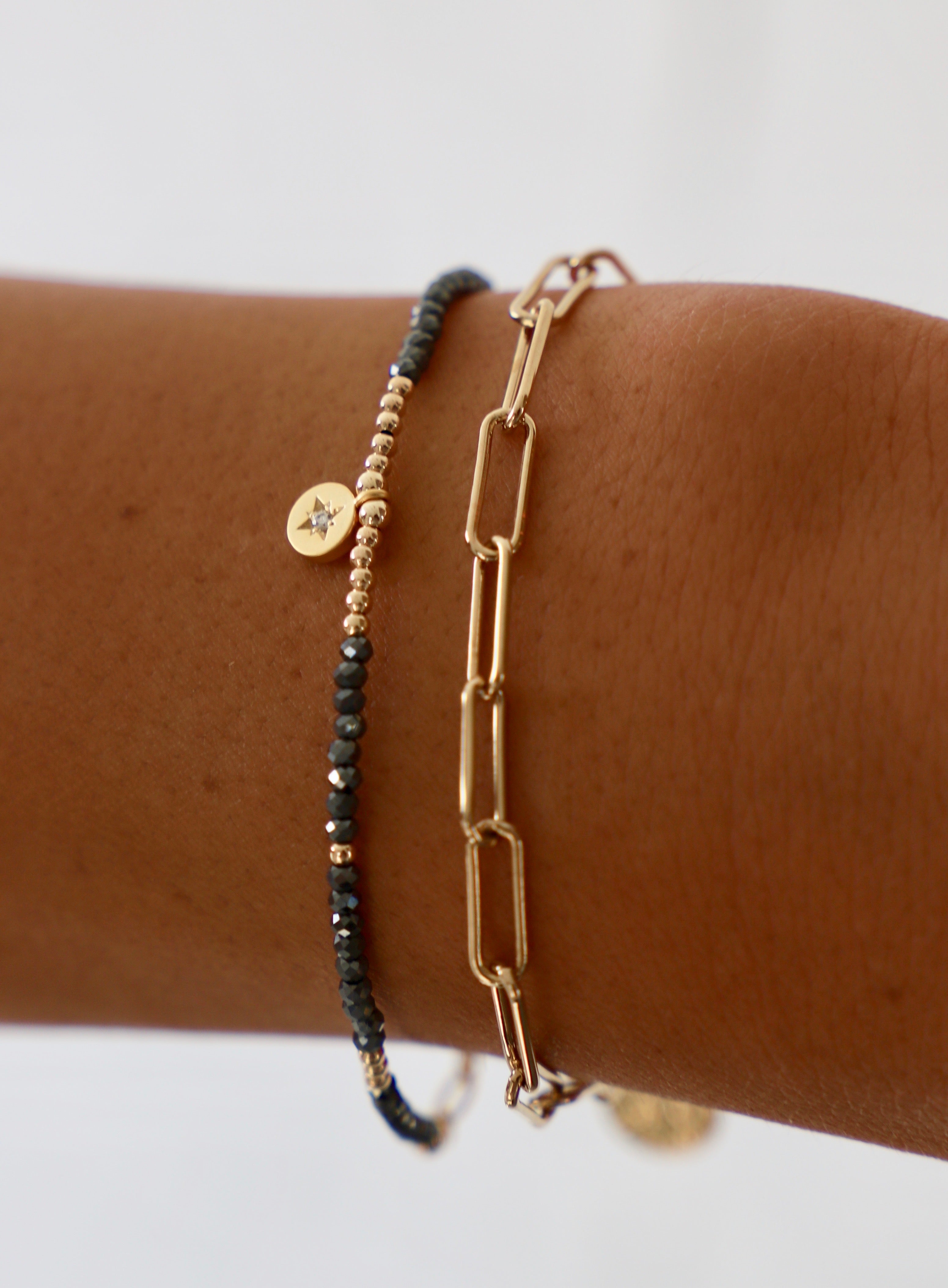 Round CZ star pendant bracelet with petite crystals and gold accents alongside a paperclip gold bracelet – dainty celestial jewelry for women