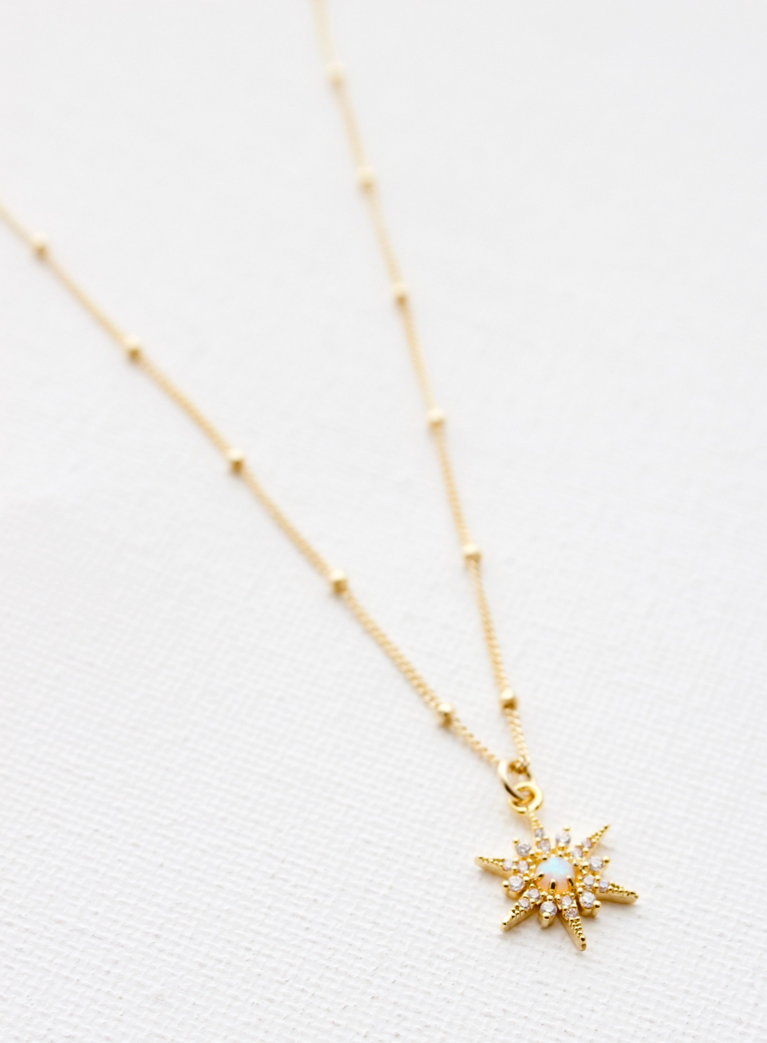 Gold necklace with a star-shaped pendant on a white background
