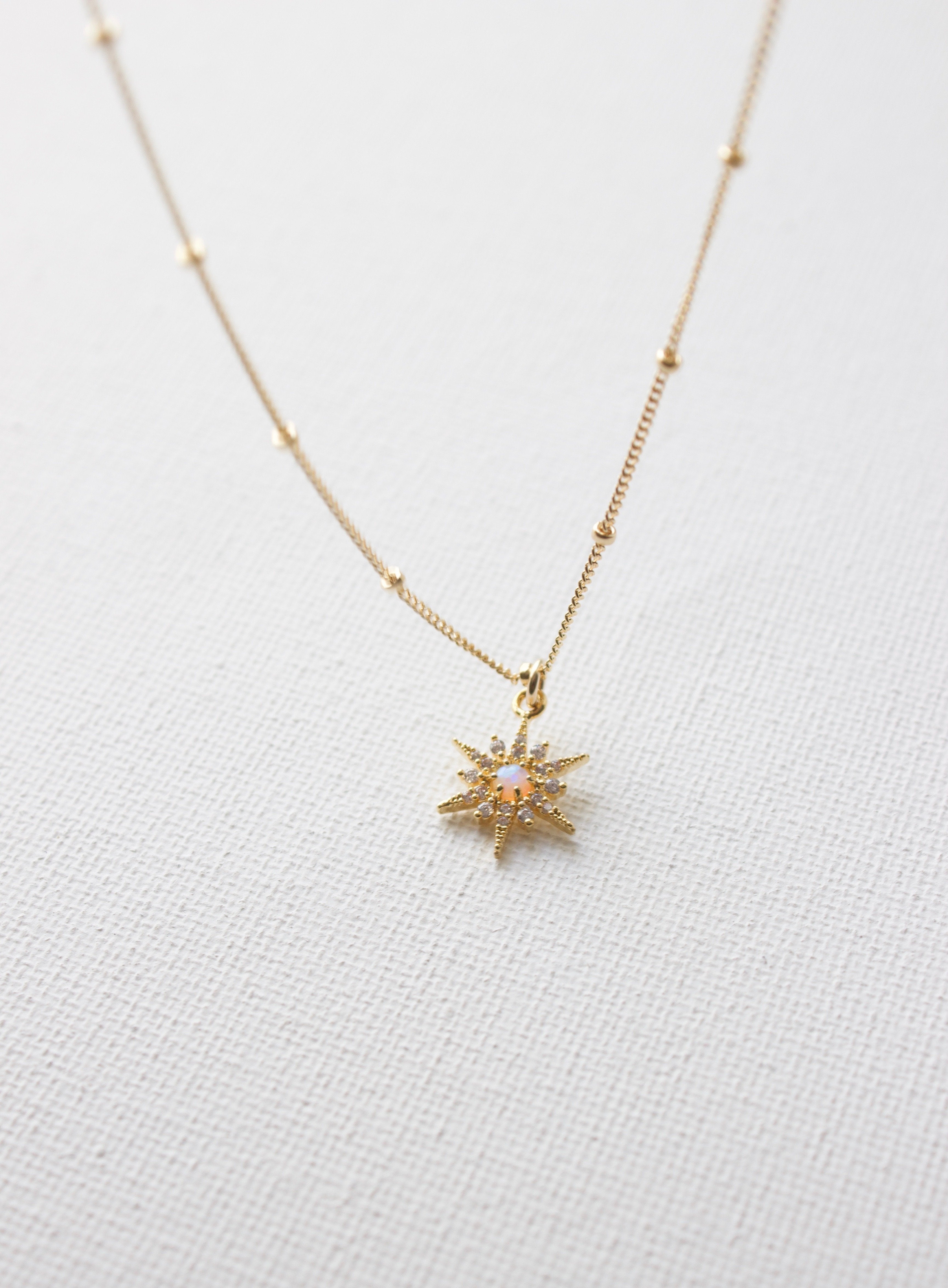 Gold necklace with a star-shaped pendant on a light gray background