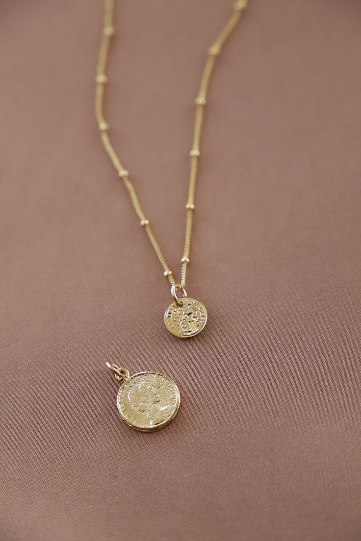 Gold necklace with three round pendants on a brown background