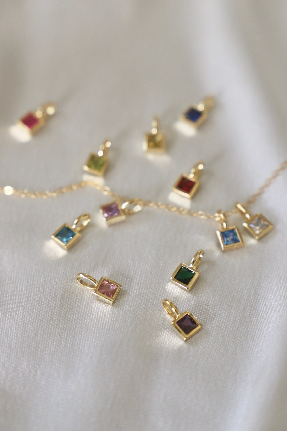 Gold jewelry set with colorful birthstone gemstones on a white fabric background