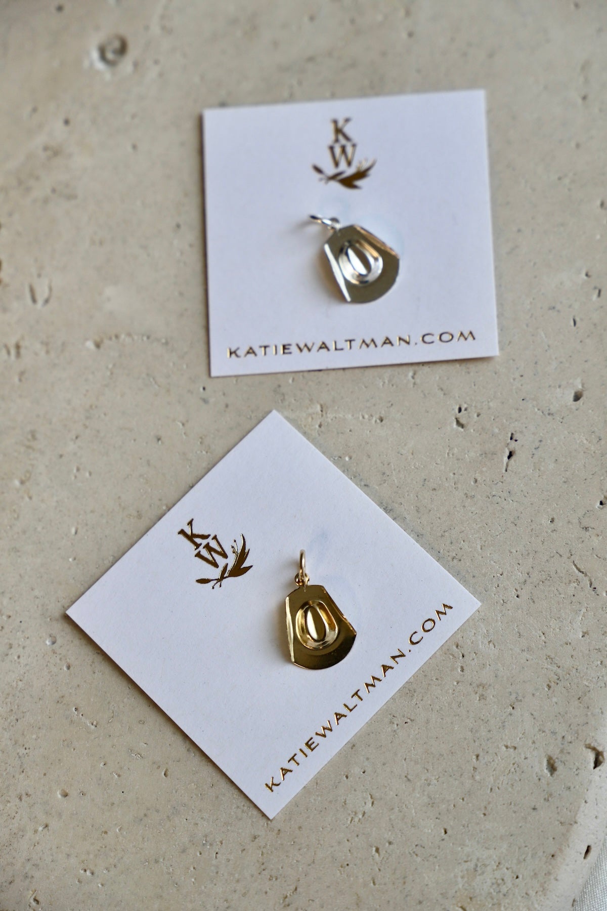 Gold pendant held between thumb and forefinger against a dark background