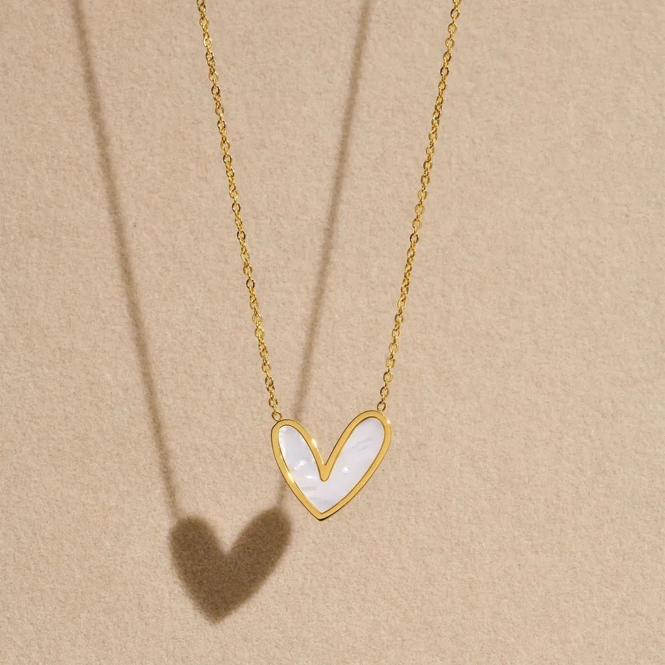 Gold necklace with a heart-shaped pendant on a beige background