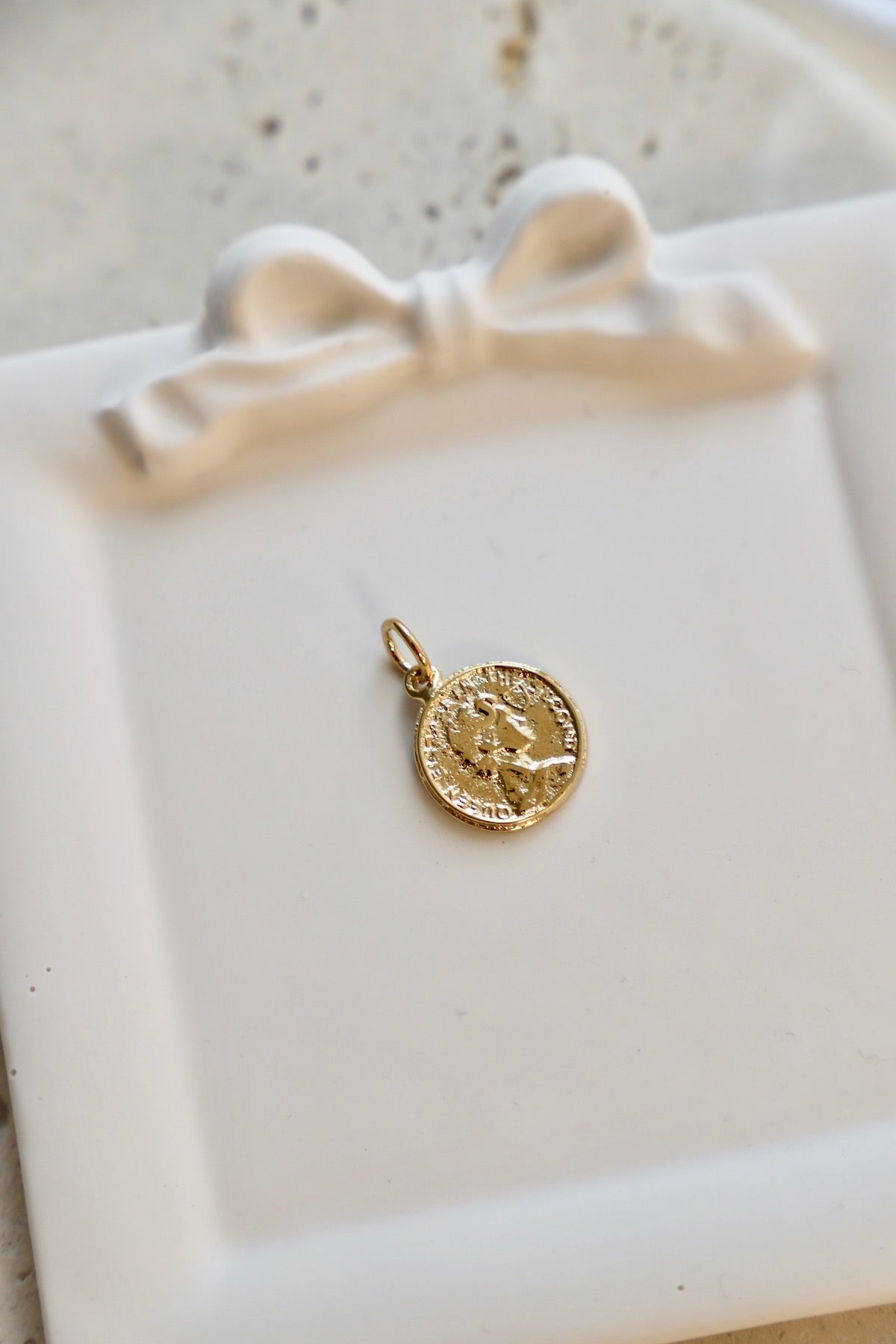 Gold pendant on a white dish with a bow