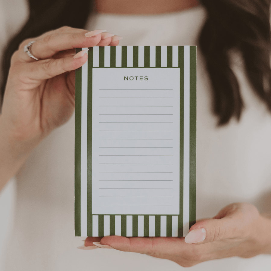 Notepad with green and white striped design held by a person
