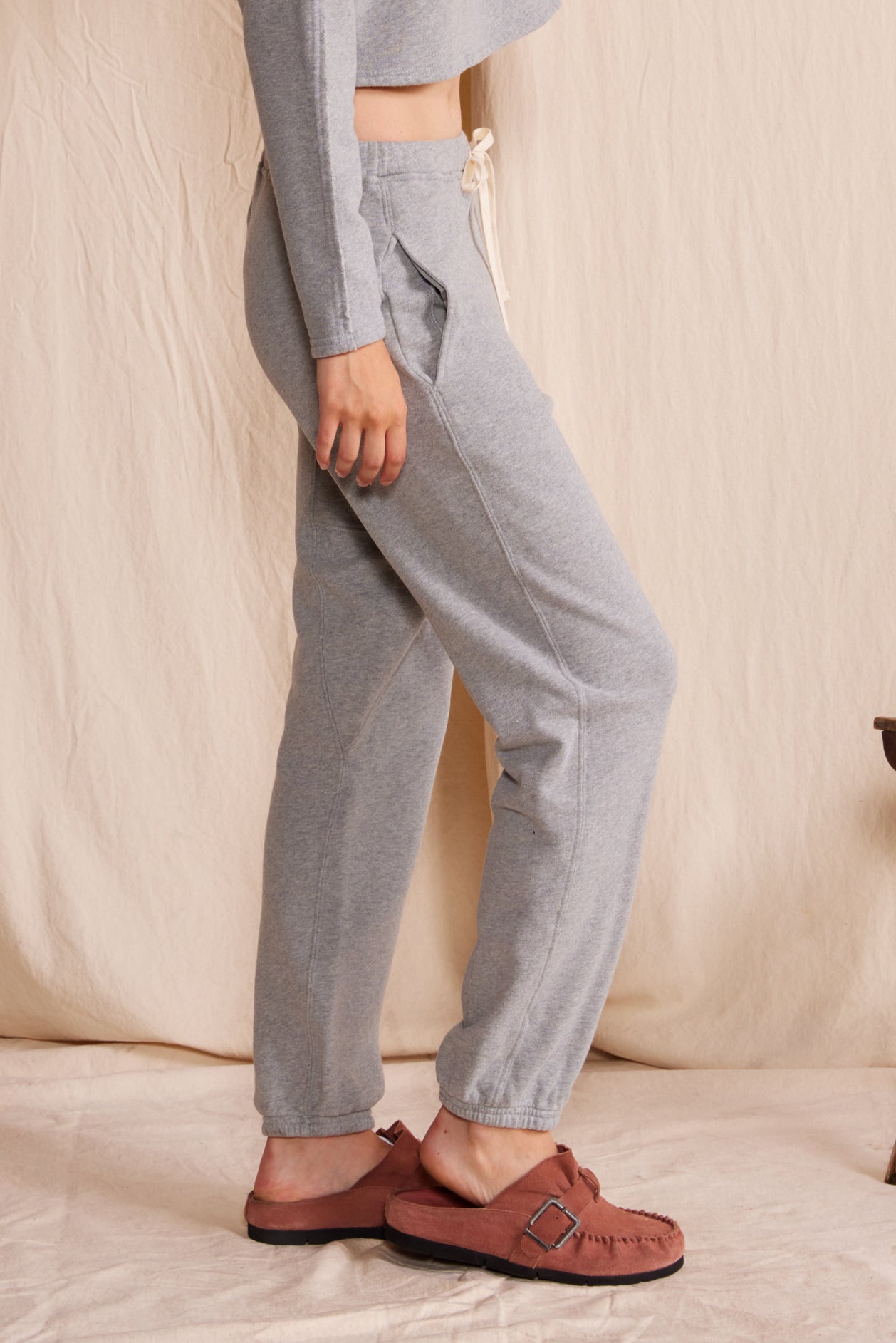 Person wearing gray pants and brown shoes on a beige background